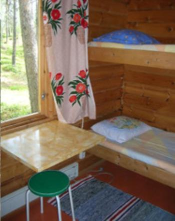 a wooden cabin with a desk and a green stool at Lemmenjoen Lumo - Nature Experience & Accommodation in Lemmenjoki