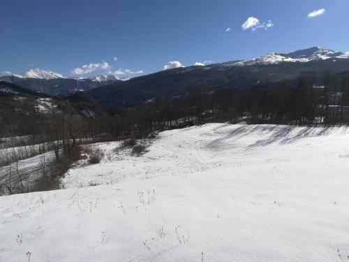 una ladera cubierta de nieve con montañas en el fondo en B&b La Violetta, en SantʼAnna Pelago