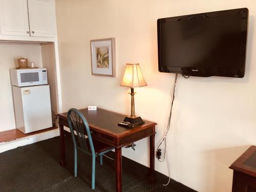 Habitación con escritorio y TV en la pared. en Los Feliz Hotel en Glendale