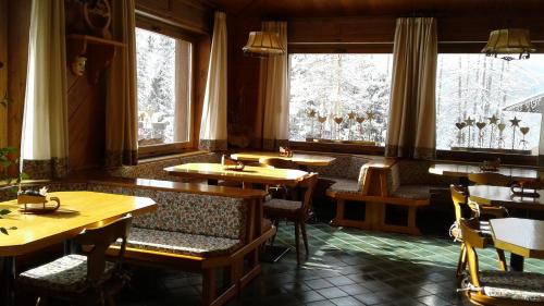 un ristorante con tavoli e sedie in legno e finestre di Meublè Barancio a San Vito di Cadore