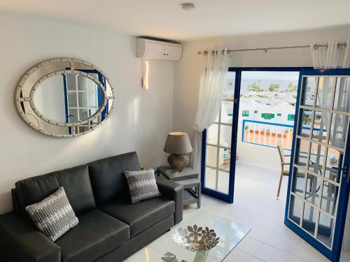 een woonkamer met een zwarte bank en een spiegel bij Forever Views in Puerto del Carmen