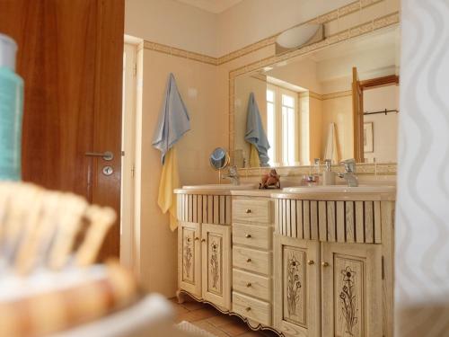 Un baño con lavabo y un espejo grande. en Casa Eugenia, en Sesimbra