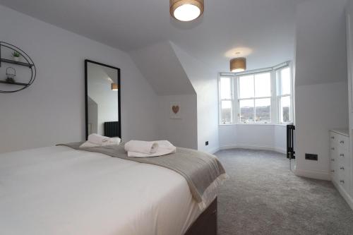 a white bedroom with a large bed and a large mirror at Dollar Apartments-41 Bridge Street in Dollar