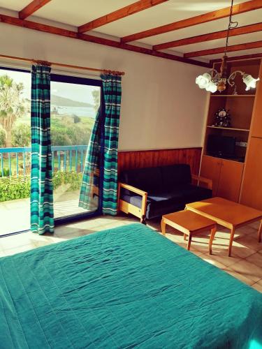 a bedroom with a bed and a couch and a large window at Kanalli Apartments in Pomos