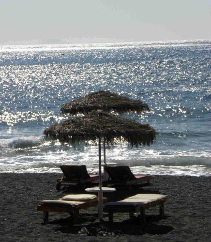 two chairs and an umbrella on the beach at Thera Incognita Studios in Perissa
