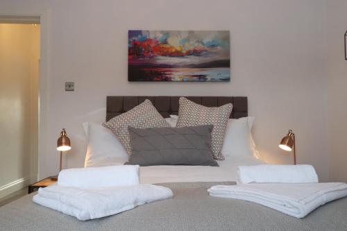 Dollar Apartments-39 Bridge Street في دولار: سرير ابيض ومخدات ولوحة على الحائط