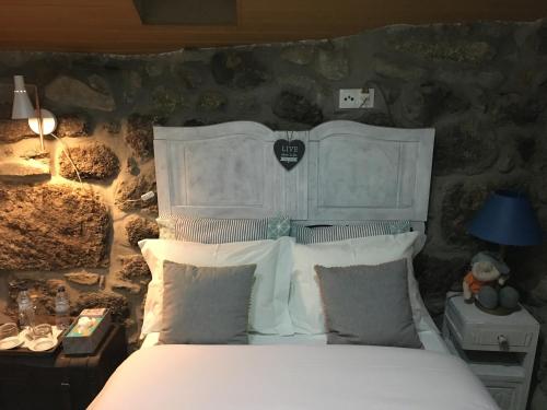 1 dormitorio con cama blanca y pared de piedra en Cantinho da Du, en Lamego