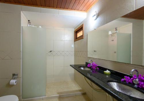 a bathroom with two sinks and a shower with a mirror at LAGO HOTEL PIPA - TlBAU DO SUL in Pipa