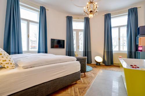 a bedroom with a bed with blue curtains and a chandelier at Leuhusen Collection Vienna, Wien in Vienna