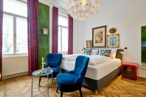 a bedroom with a bed and two blue chairs at Leuhusen Collection Vienna in Vienna