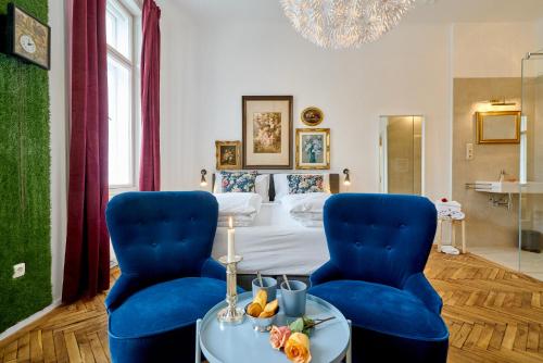 a hotel room with a bed and two blue chairs at Leuhusen Collection Vienna, Wien in Vienna