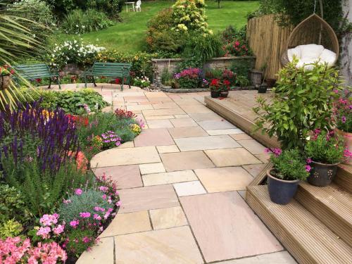 a garden with flowers and a patio with benches at Castlecroft Bed and Breakfast in Stirling