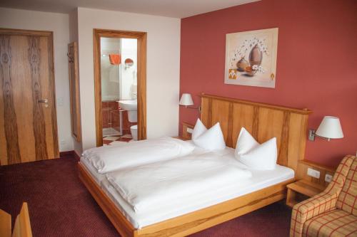 a bedroom with a bed and a chair at Gasthof zum Bäckerwirt in Chamerau
