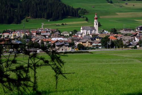 a small town in a green field with a tower at Haus Cosso in Villabassa