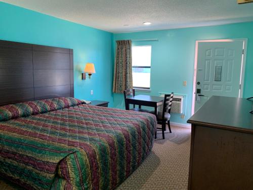 a hotel room with a bed and a desk and a table at Scottish Inn - Clanton in Clanton