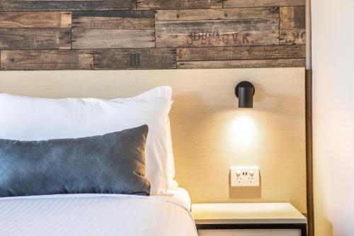 a bedroom with a bed and a wooden headboard at Nightcap at Westside Hotel in Laverton