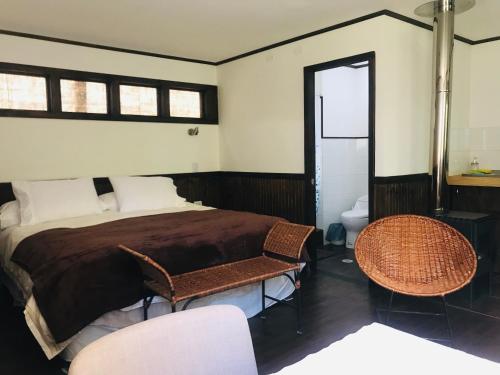 a bedroom with a bed and two chairs and a toilet at Nube Austral Patagonia in Cochrane