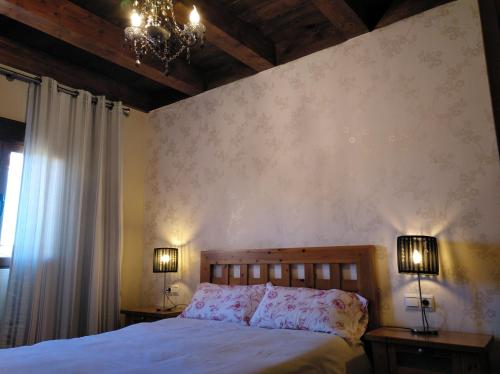 a bedroom with a bed with two lamps and a chandelier at Apartamentos La Casa Del Grial in Toledo