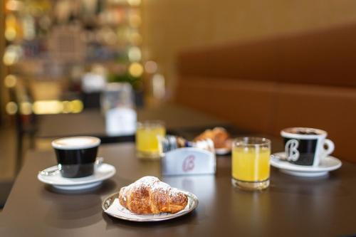 a table with cups of coffee and croissants and orange juice at B&B PonteMuto in San Pier Niceto