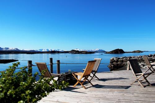a group of chairs sitting on a dock next to the water at Sveggvika Guesthouse in Averoy