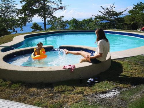 two women sitting in a pool with a girl in a raft at Cuestas Beach Resort and Restaurant in Badian