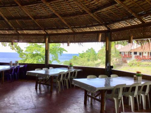 a restaurant with tables and chairs and a view of the ocean at Cuestas Beach Resort and Restaurant in Badian