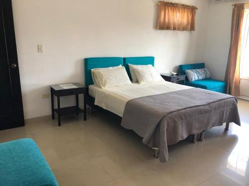 1 dormitorio con 1 cama grande y 2 sillas azules en Apartamentos Vonblon, en San Andrés