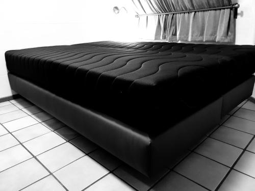 a black bed sitting on a tiled floor in a room at Iglo Bungalow 17 in Chaam