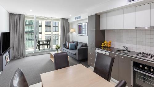 a kitchen and living room with a table and chairs at Oaks Adelaide Embassy Suites in Adelaide