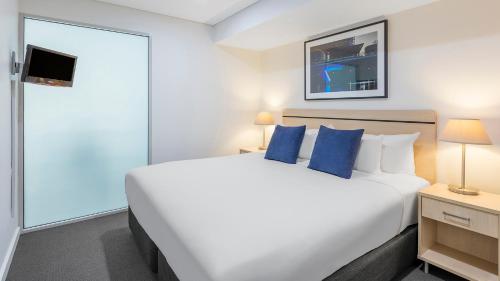 a bedroom with a large bed with blue pillows at Oaks Adelaide Embassy Suites in Adelaide