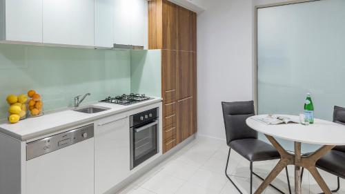 a kitchen with a sink and a table with chairs at Oaks Adelaide Embassy Suites in Adelaide