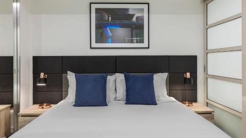 a bedroom with a large bed with blue pillows at Oaks Adelaide Embassy Suites in Adelaide