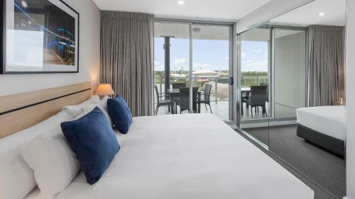 
a hotel room with a large bed and a large window at Oaks Adelaide Embassy Suites in Adelaide
