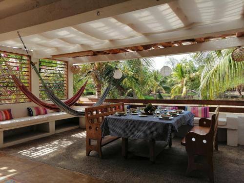 Una habitación con mesa, sillas y hamacas. en Casa de Playa Laguito Shangai, en Moñitos