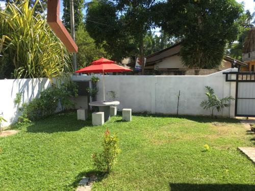 a patio with a table and an umbrella in a yard at Villa N in Unawatuna
