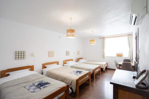 um grupo de quatro camas num quarto em Beach Side Inn Shirahama em Shimoda