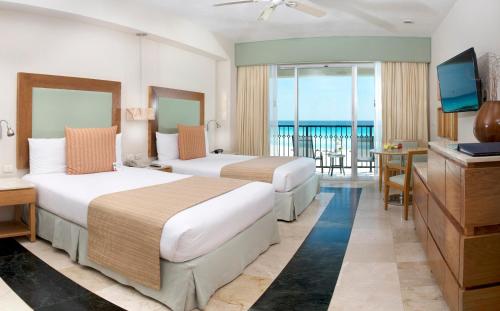 Grand Park Royal Cancun - All Inclusive في كانكون: غرفه فندقيه سريرين وتلفزيون