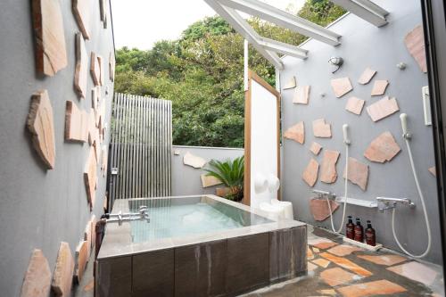 a bathroom with a hot tub and a shower at Beach Side Inn Shirahama in Shimoda
