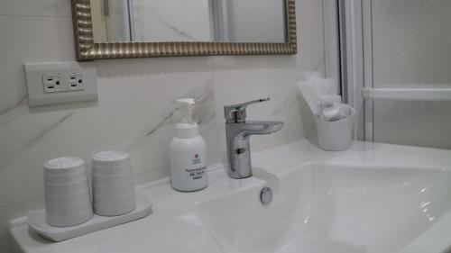 a white bathroom with a sink and a mirror at Joy Hotel in Taitung City