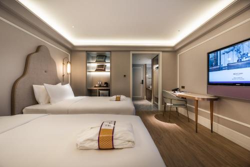 成都Chengdu Taikoo Li Chunxi Mercure Hotel的一间配有两张床和一台平板电视的酒店房间