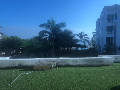 a field of grass with palm trees and a building at Almasi Beach Apartment - Freshly Renovated in Mombasa
