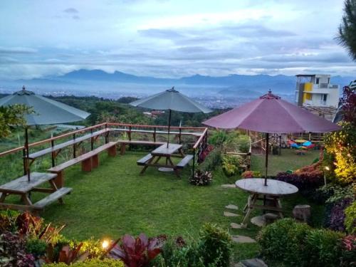 a garden with picnic tables and umbrellas on a hill at Valle Verde Villas in Bandung