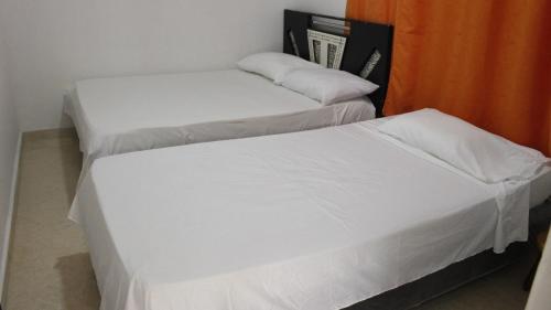 two beds in a room with white sheets at Apartamentos Arpushana in Ríohacha