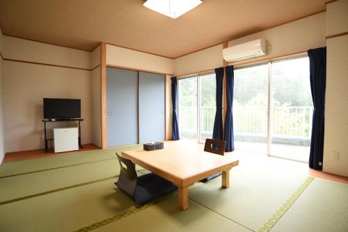 a living room with a table and a large window at Alaise De Bale Shirahama in Shirahama