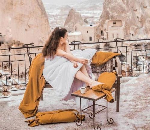 a woman sitting on a chair on a balcony at Elite Cave Suites in Goreme