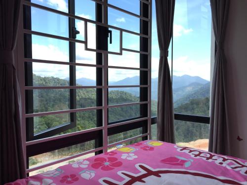 een slaapkamer met een raam met uitzicht op de bergen bij 12pax Golden Shine Homestay @Midhills Genting in Genting Highlands