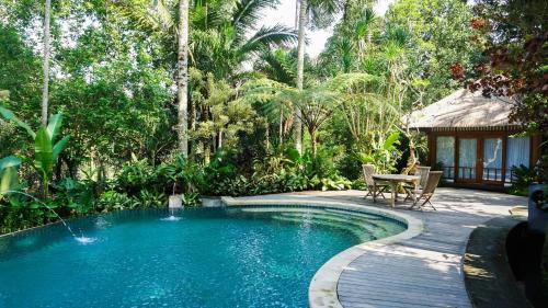 a swimming pool in a garden with a table and chairs at Umah Lawas Villa Ubud in Ubud