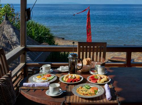 a table with plates of food and the ocean at Jasri Bay Hideaway in Jasri