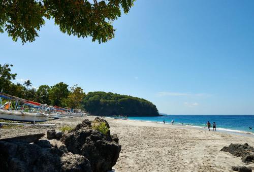 a beach with people and a boat on the water at Jasri Bay Hideaway in Jasri