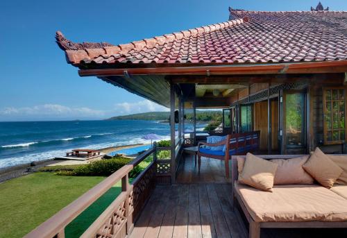 a house with a balcony with a view of the ocean at Jasri Bay Hideaway in Jasri